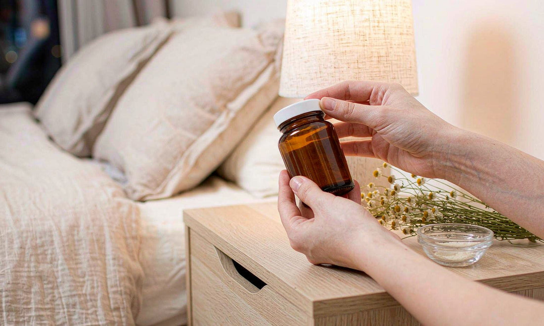 Hands holding an unbranded amber jar beside chamomile flowers on a bedside table