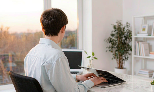 Person from behind closing a laptop at a sunset window