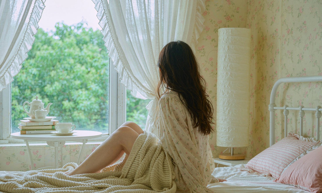 Woman seen from behind winding down on a bed at dusk